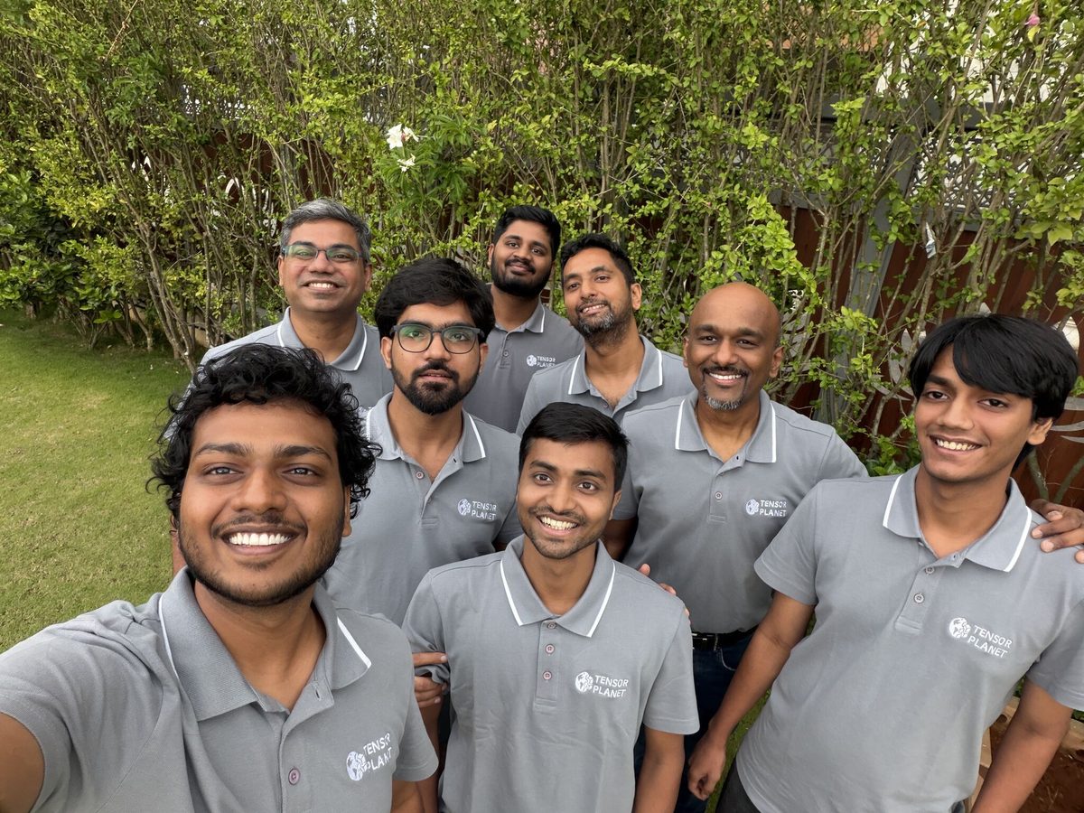 Selfie of nine Tensor Planet team members in matching gray branded polo shirts in a garden